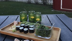 A wooden tray with sushi, seaweed salad, and sea shells on a table.