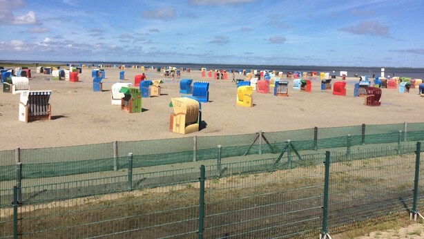 A beach with numerous colorful beach huts.