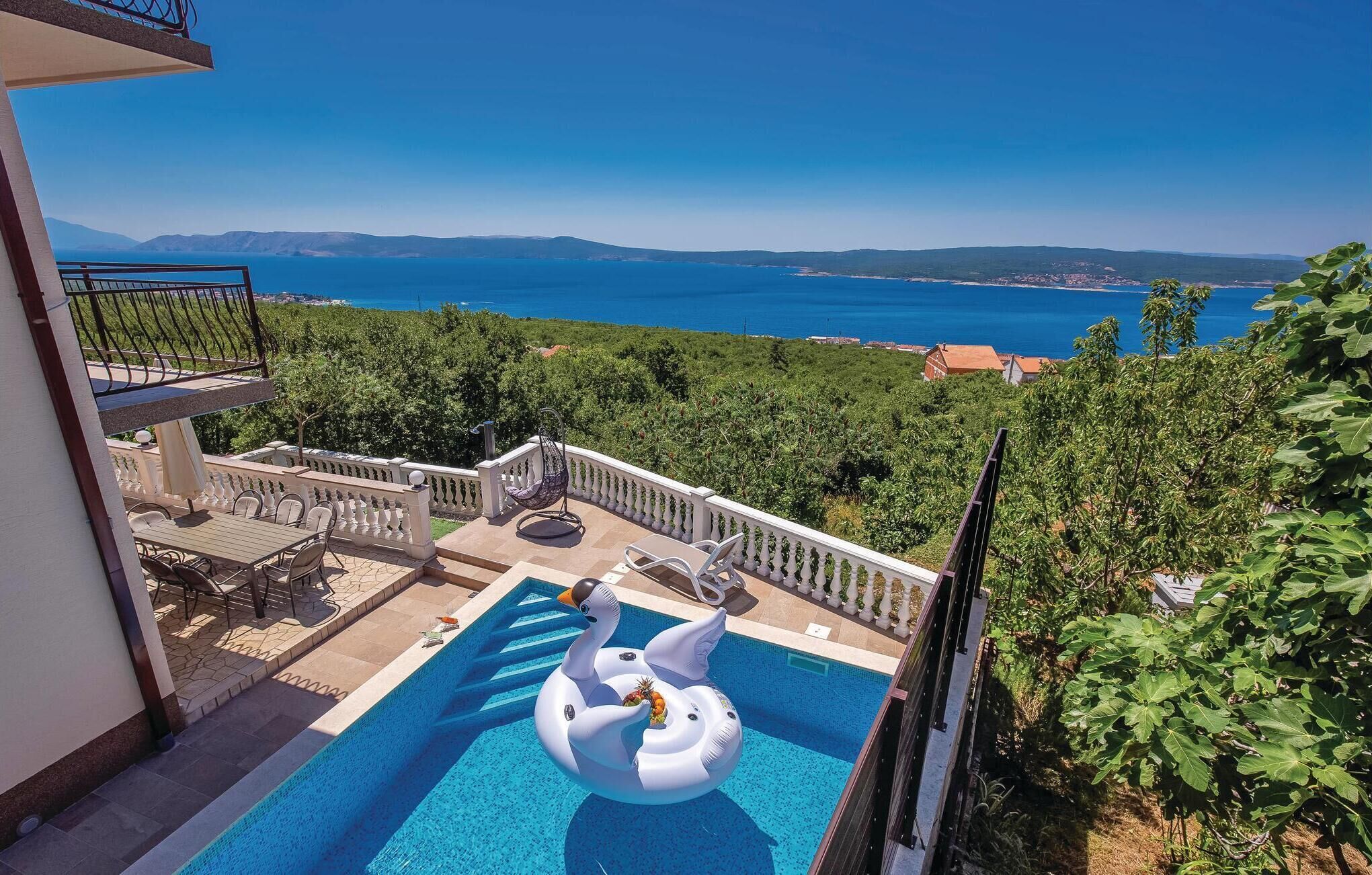 Una piscina con un galleggiante a forma di cigno, arredi da esterno e vista sul mare e sulle colline.