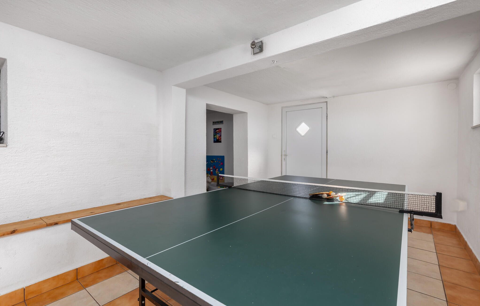Ein Tischtennis-Tisch in einem Raum mit weißen Wänden und Holzboden.