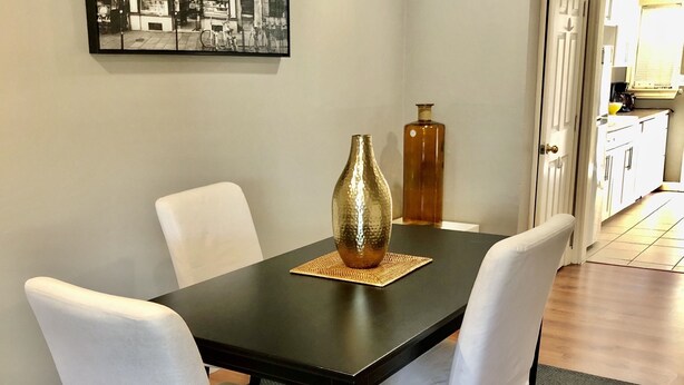 Ein Esstisch mit vier Stühlen, einer Vase und einem gerahmten Bild an der Wand.