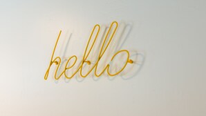 A wall with a simple, modern design featuring the word "hello" in a cursive, yellow font.