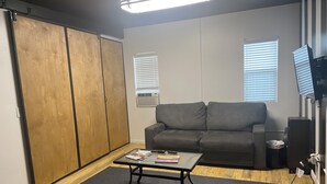 A living room with a grey sofa, a glass coffee table, and a wooden wardrobe.