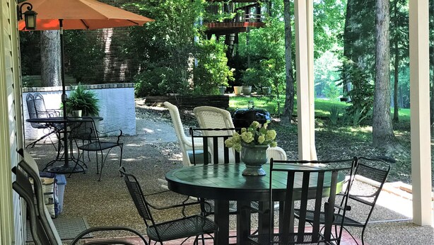 An outdoor patio with a round table and chairs, surrounded by a brick wall and trees. -  Let the vacationing begin! (Hot Springs Village)