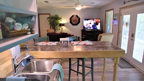 A kitchen with a granite countertop, stainless steel sink, and a dining area with a table and chairs. -  Let the vacationing begin! (Hot Springs Village)