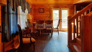 A wooden interior with a staircase, a dining area with chairs, a lamp, and a framed picture on the wall. - Stay at Nina's Cabin in beautiful Blue Ridge, Ga "Gateway to the Smokeys" (Blue Ridge)