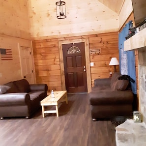 Relax in this inviting living room with two sofas, a coffee table, and a stone fireplace.