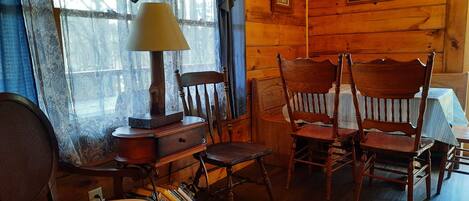Un intérieur en bois comprenant un bureau, deux chaises, une lampe et une fenêtre avec des rideaux.