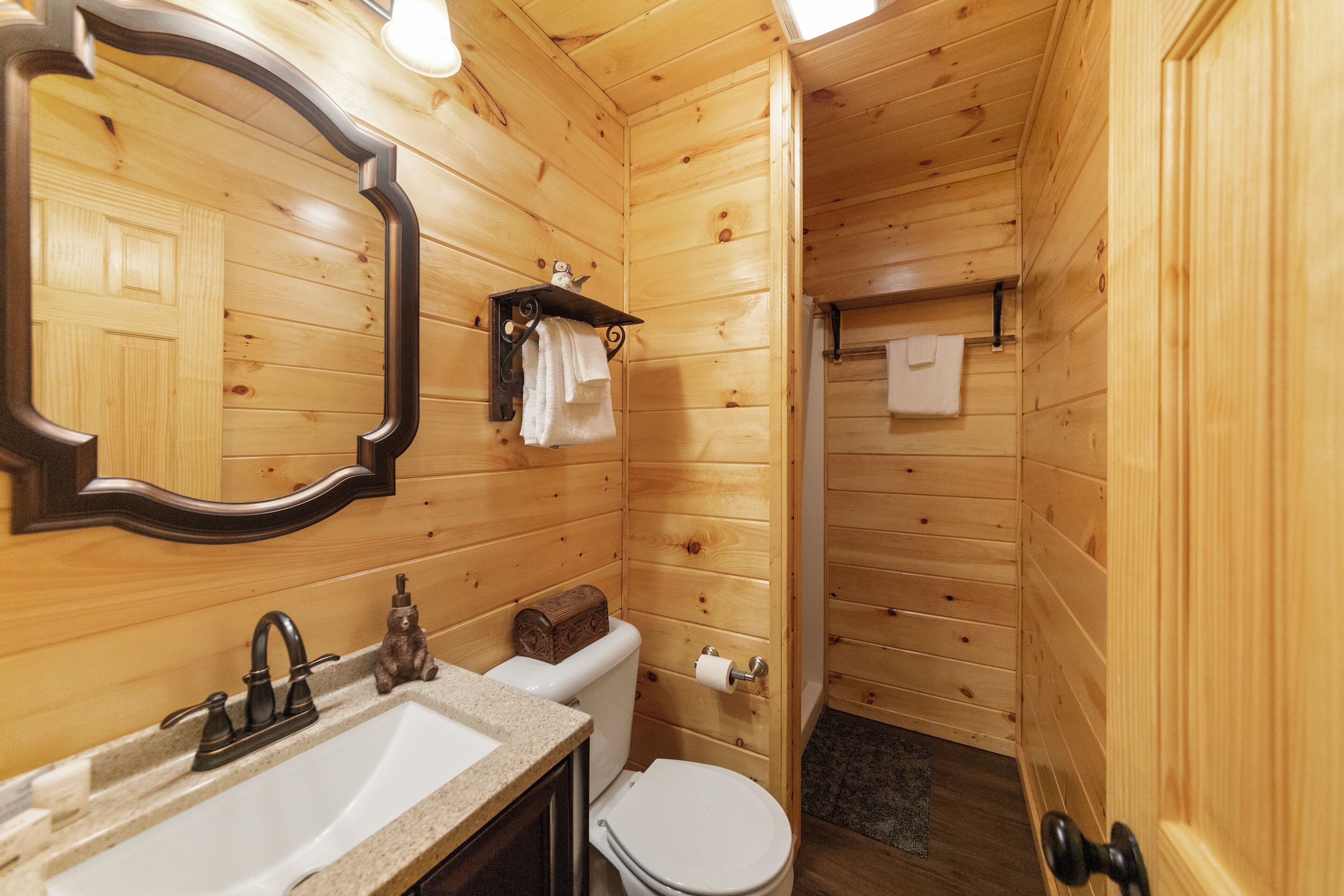 A wooden cabin bathroom with a sink, toilet, and mirror.