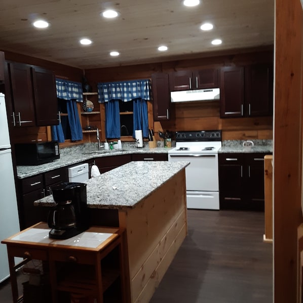 Kitchen area with a stove, microwave, sink, and coffee maker, offering a convenient space for meal preparation.