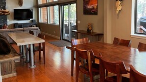 Un comedor amplio con una gran mesa de madera y sillas, televisor integrado y chimenea de piedra.