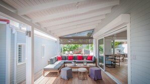 Una zona living esterna coperta, con un divano componibile, un tavolino da caffè e un tavolo da pranzo.