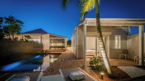 Un moderno resort con piscina, tumbonas y una zona exterior cubierta.