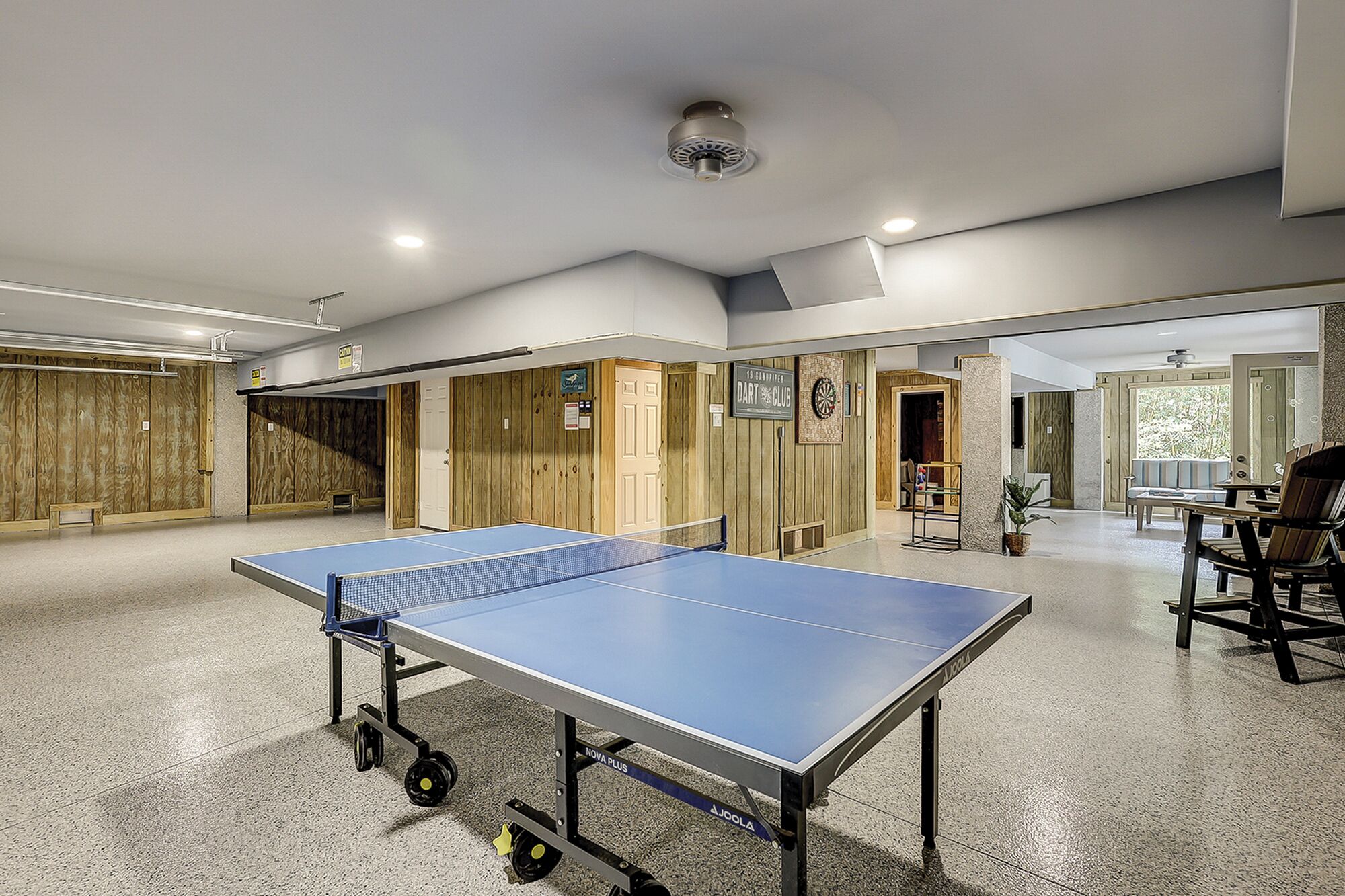 Una mesa de ping pong en una habitación con paredes de madera y un dardo.