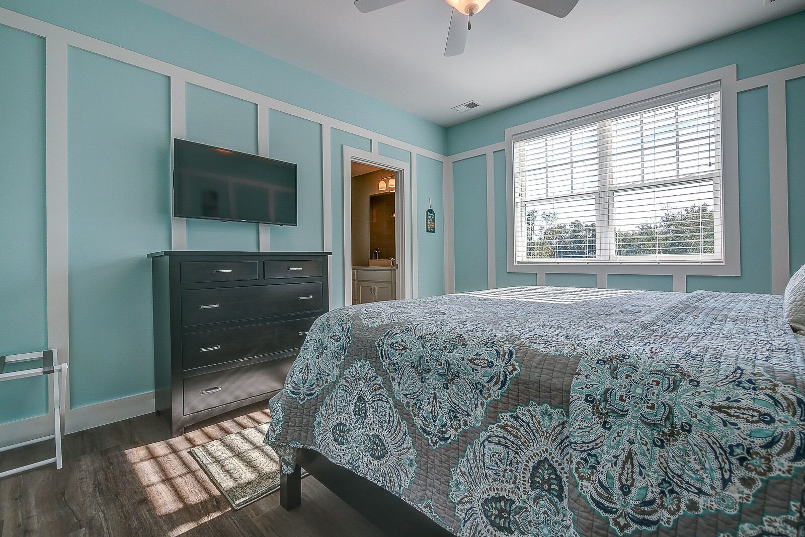 A bedroom with a bed, dresser, and TV.
