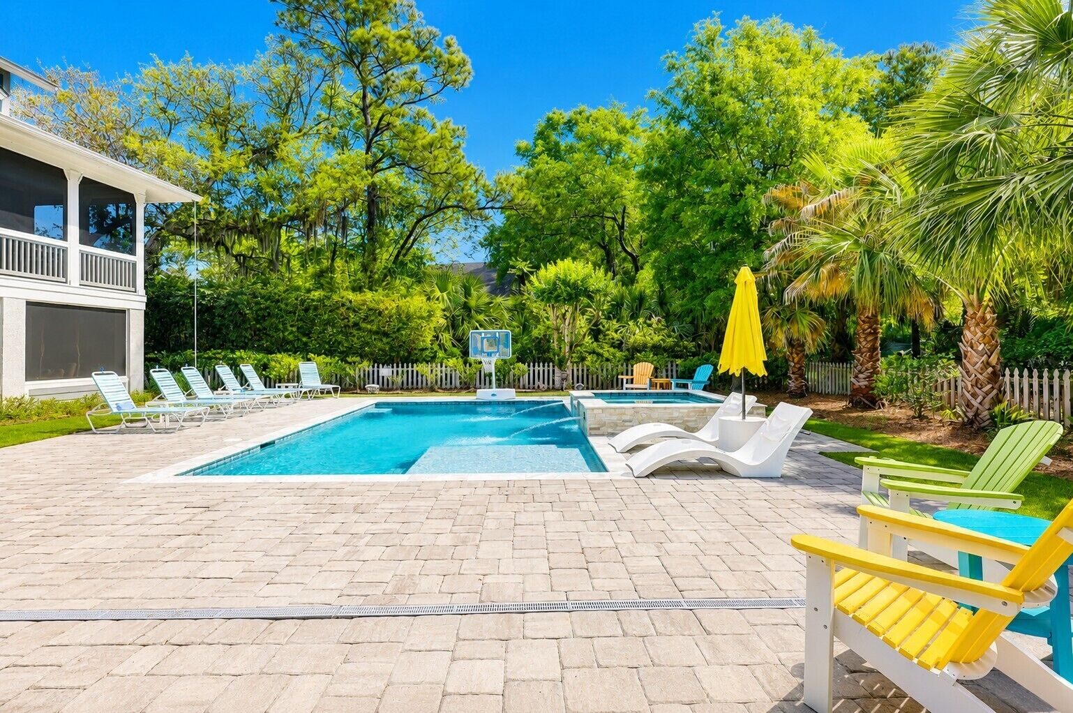 A swimming pool with lounge chairs and a basketball hoop.