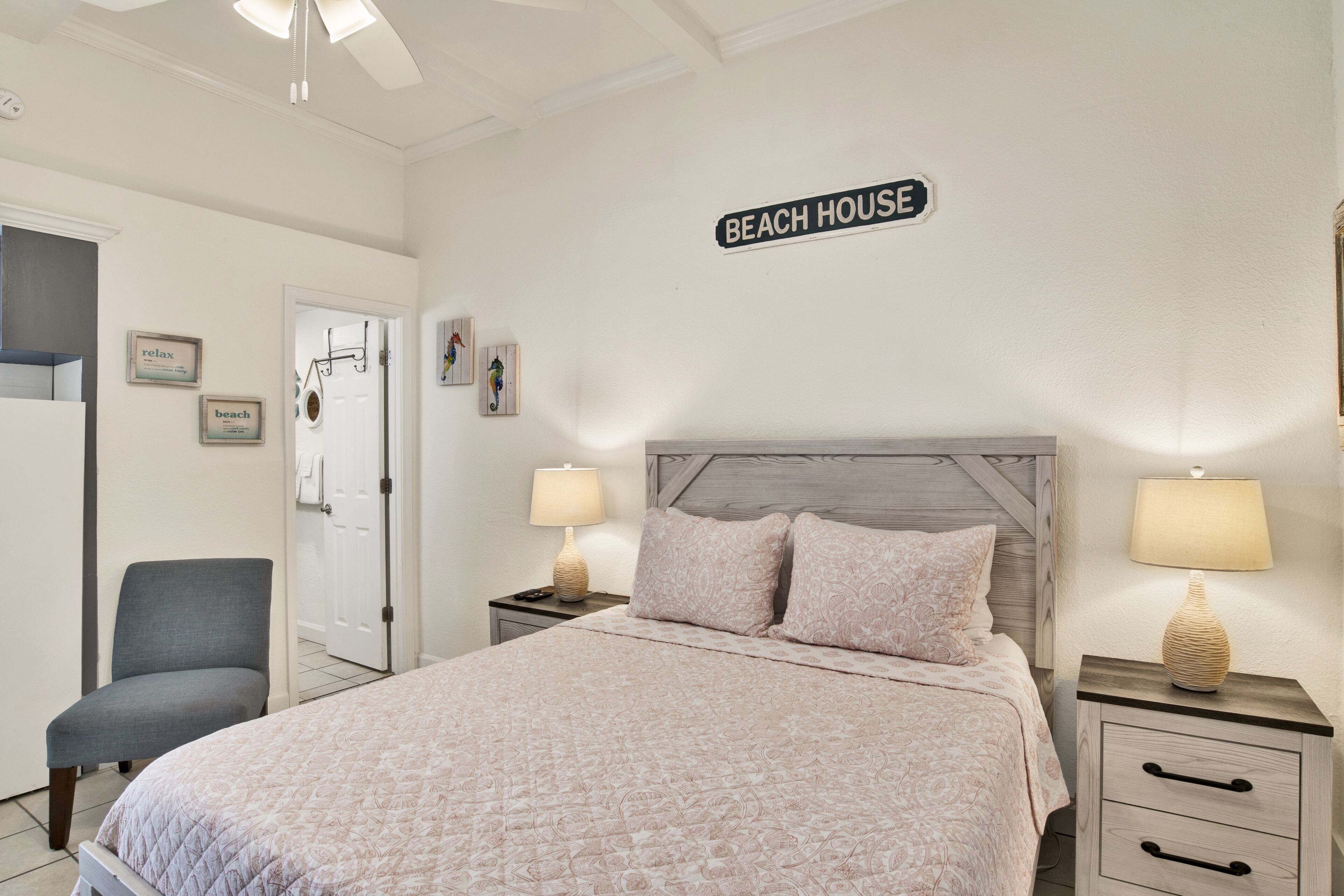 A bedroom with a bed, two bedside tables with lamps, a chair, and a door.