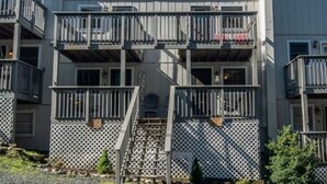 Un edificio residencial de varios pisos con balcones, una escalera central y un cerramiento de celosía.
