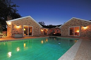 A poolside area with a brick building, a pool, and outdoor seating. - Pool side in Port Orange, Near beach, Gated Community, Bikers Welcome!Golf! (Port Orange)