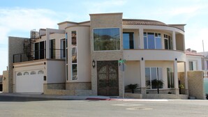 Una casa moderna de dos pisos con garaje, ventanas amplias y un balcón.