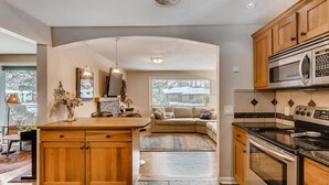 Une cuisine moderne avec des meubles en bois, un îlot central, un four encastré et un four à micro-ondes.