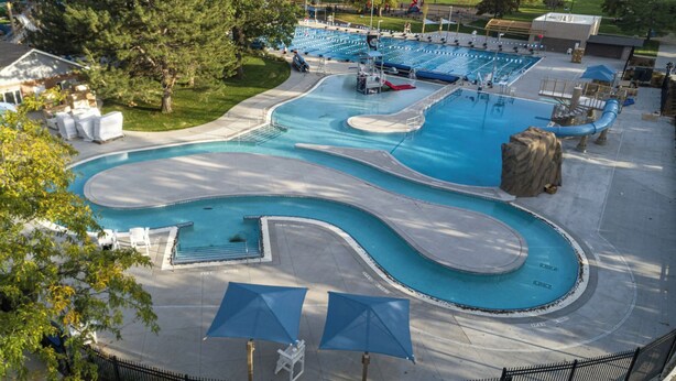 Une piscine au design sinueux, entourée de chaises longues et de parasols.