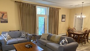 A living room with two grey sofas, a wooden coffee table, and a dining area with a wooden table and chairs. - Castle Hill Resort Condo (with on-site Aveda Spa) (cavendish)