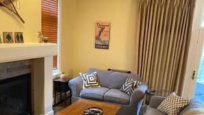 A living room with a fireplace, a grey sofa set, a wooden coffee table, and a patterned rug. - Castle Hill Resort Condo (with on-site Aveda Spa) (cavendish)
