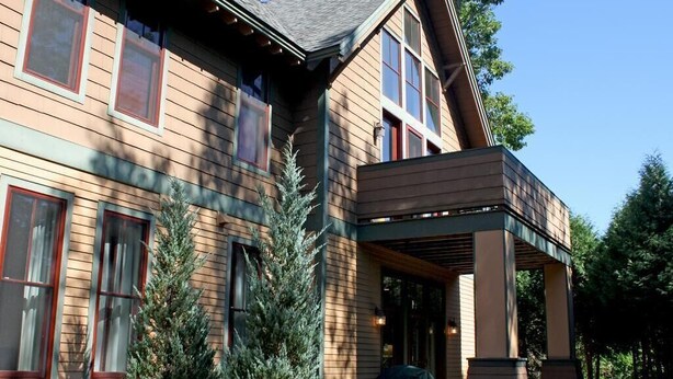 A two-story house with a covered porch and a small tree in the front yard. - Castle Hill Resort Condo (with on-site Aveda Spa) (cavendish)