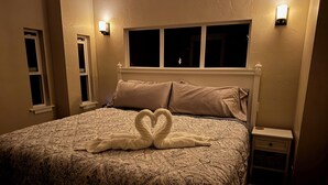 A bedroom with a patterned bedspread, two pillows, a nightstand, and a wall-mounted light fixture. - Lake House with Sauna, kayaks, S.U.P.'s, snorkeling sets and boat parking (Polson)