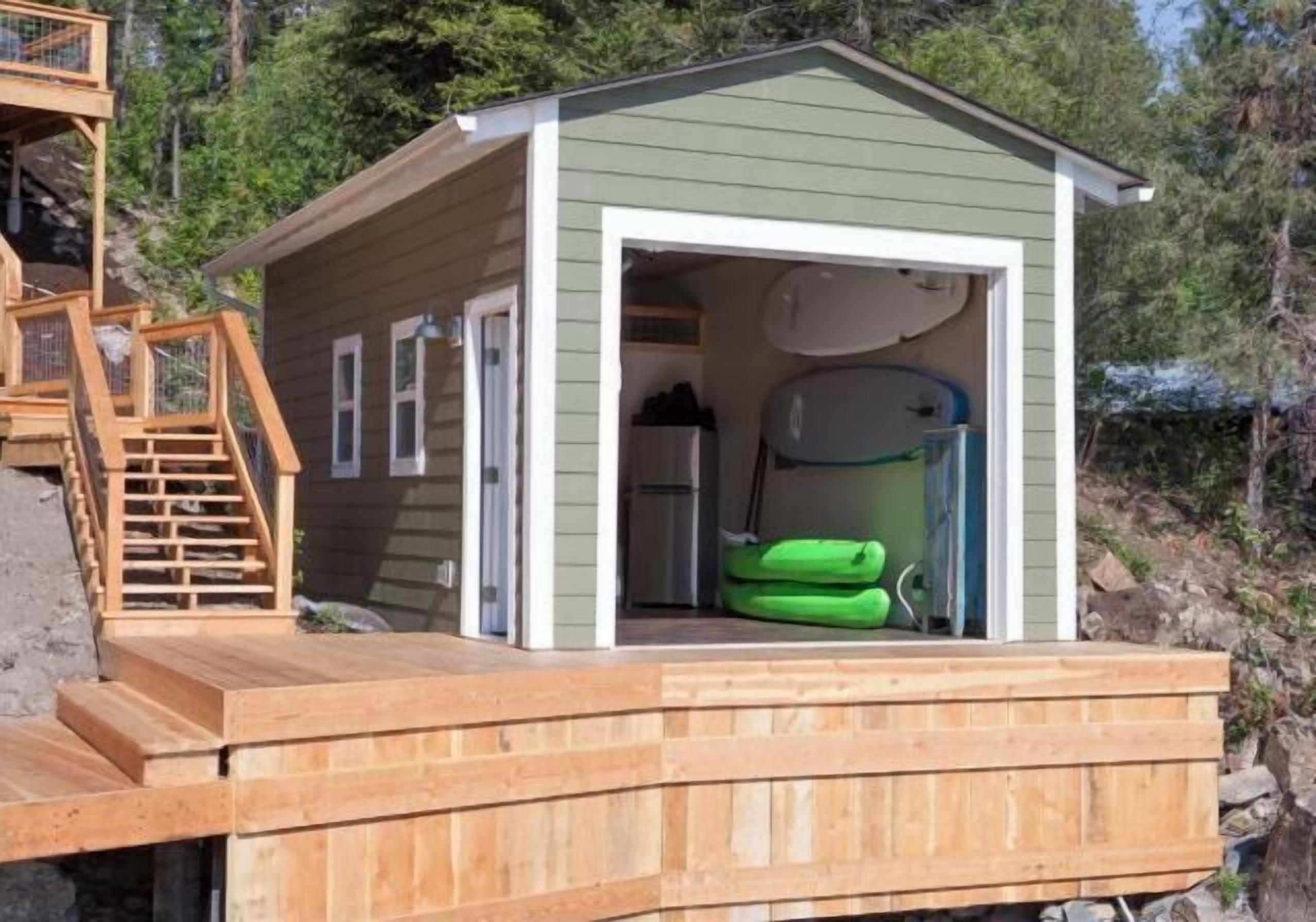 A wooden cabin with a deck, a staircase, and a sauna.