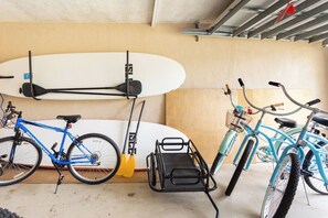 Un garaje con dos bicicletas, una tabla de surf y una tabla de remo.