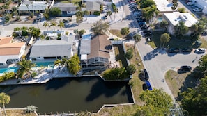 Vista aérea de una zona residencial con piscina, varias casas y coches aparcados.