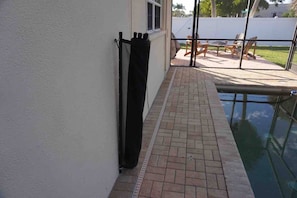 Zona junto a la piscina con patio de ladrillo, piscina y mobiliario exterior.