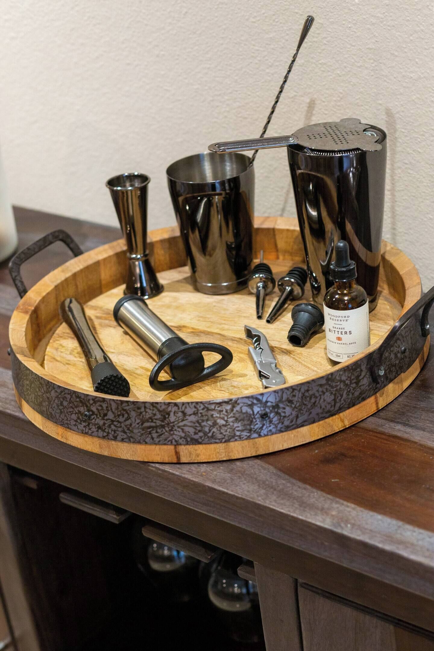 Een dienblad met diverse cocktailgereedschappen en een flesje bitters.