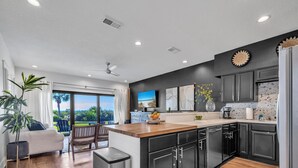 A modern kitchen with dark cabinets, a wooden countertop, and a view to the outdoors. - Palms A1: Best Prices to Be Ground Level Directly  on the Beach  (Santa Rosa Beach)