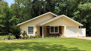 A single-story house with a gabled roof, a front porch, and a garage. - Super Clean and Super Comfortable with boat ramp under half mile down the road. (Crystal River)