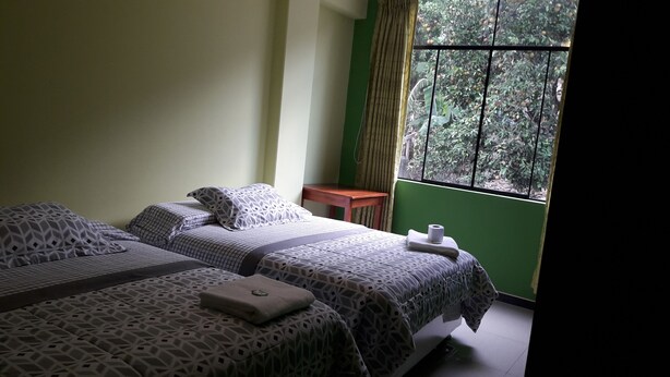 Una habitación con dos camas, una mesita y un ventanal con vistas a zonas verdes.