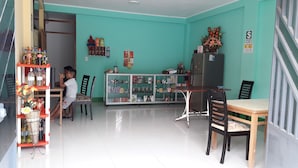 Una habitación con paredes color esmeralda, un refrigerador, una vitrina de vidrio y una mesa de comedor con sillas.