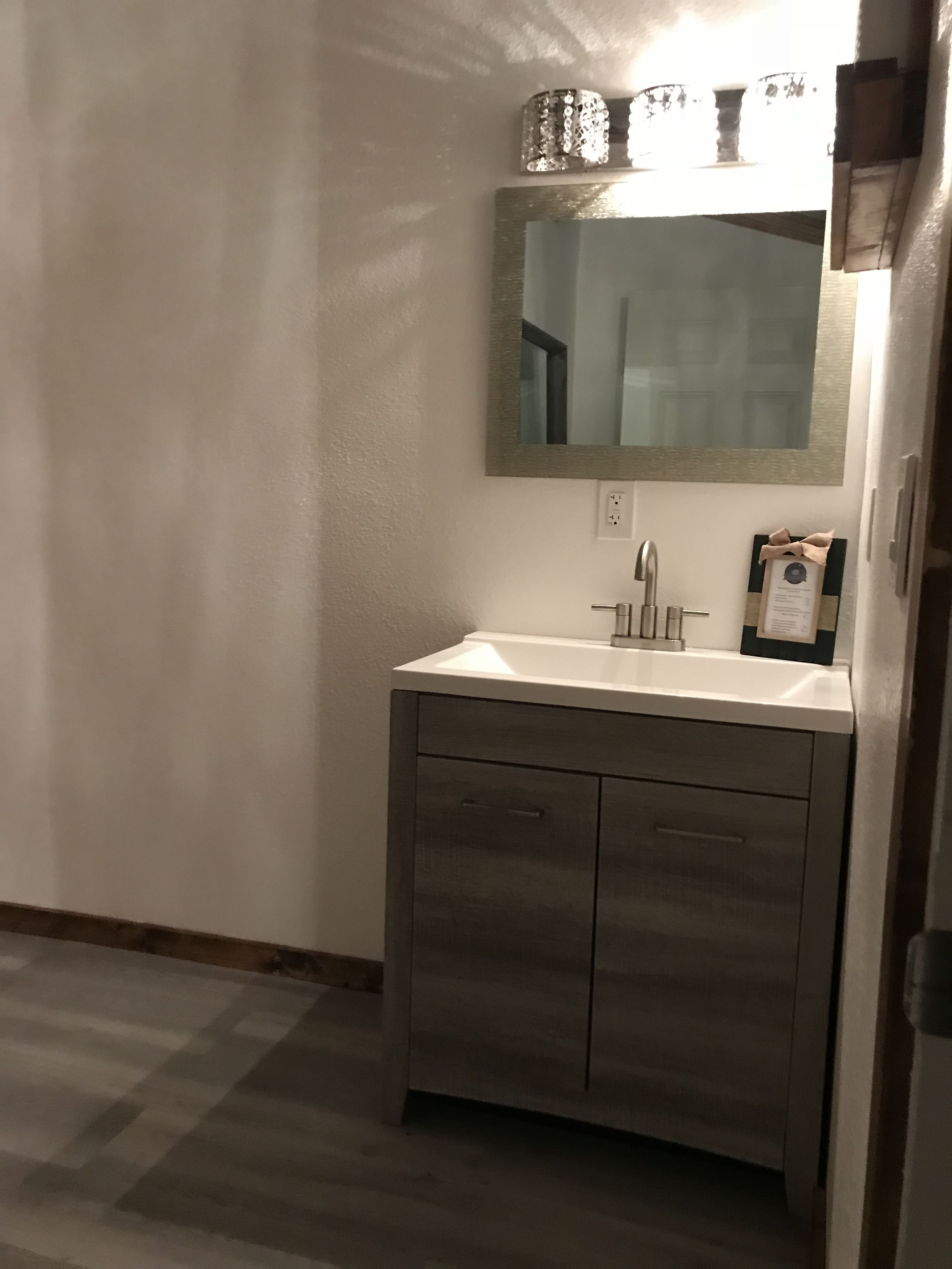 Un baño con un lavabo blanco, un espejo y un armario de madera.