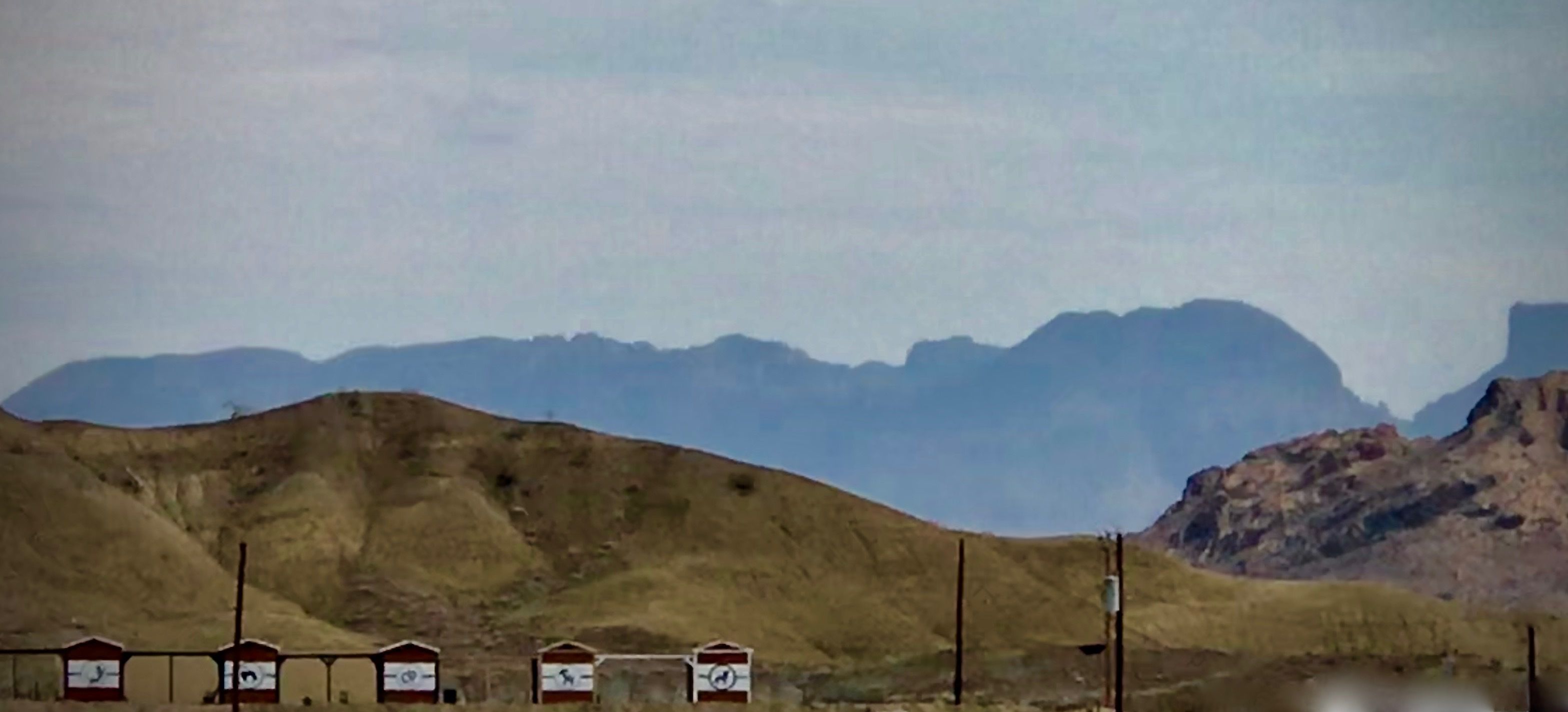 Un paysage montagneux, avec une série de bâtiments aux toits rouges au premier plan.