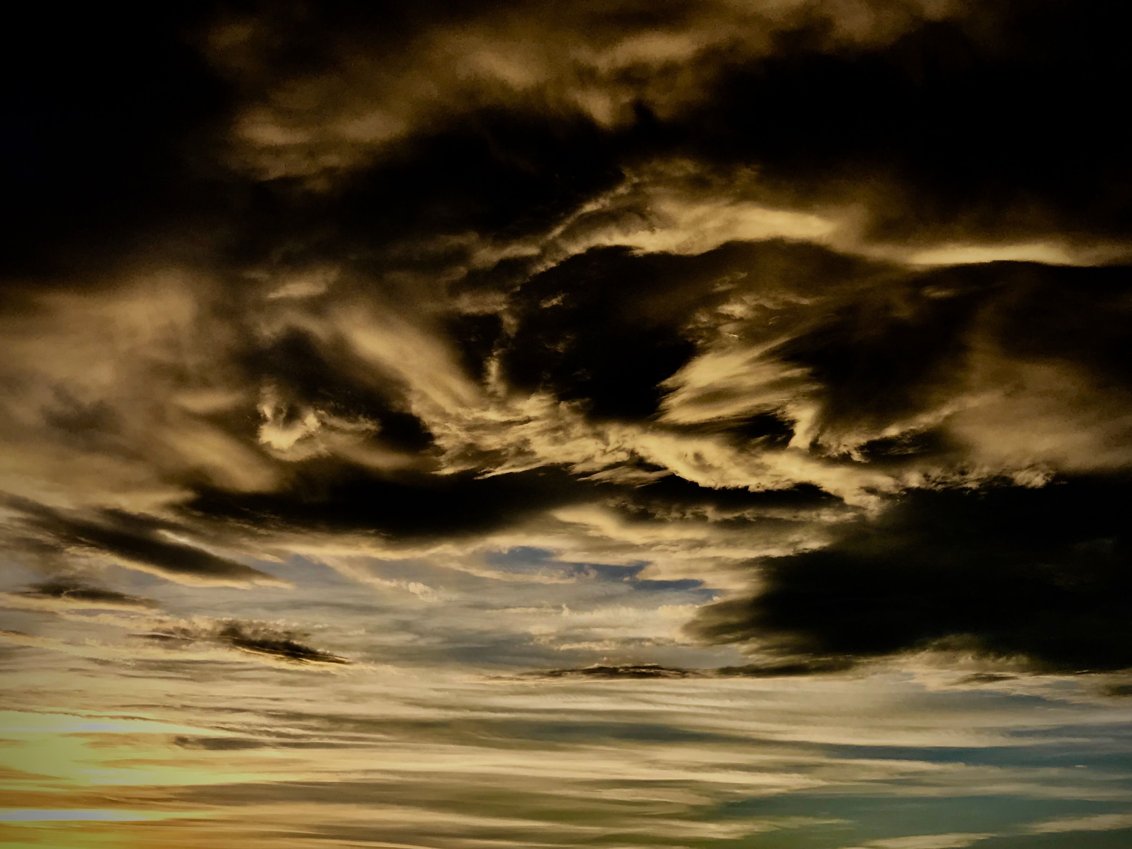 A stormy sky with dark clouds and a hint of sunlight breaking through.