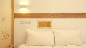 A bedroom with a wooden headboard, a wall-mounted light, and a small wooden panel above the bed.