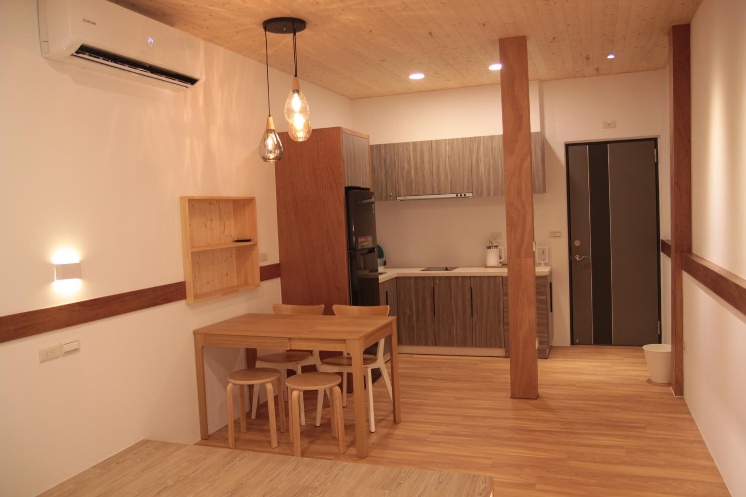 A modern kitchen with wooden cabinets, a dining area with a wooden table and chairs, and a built-in oven.