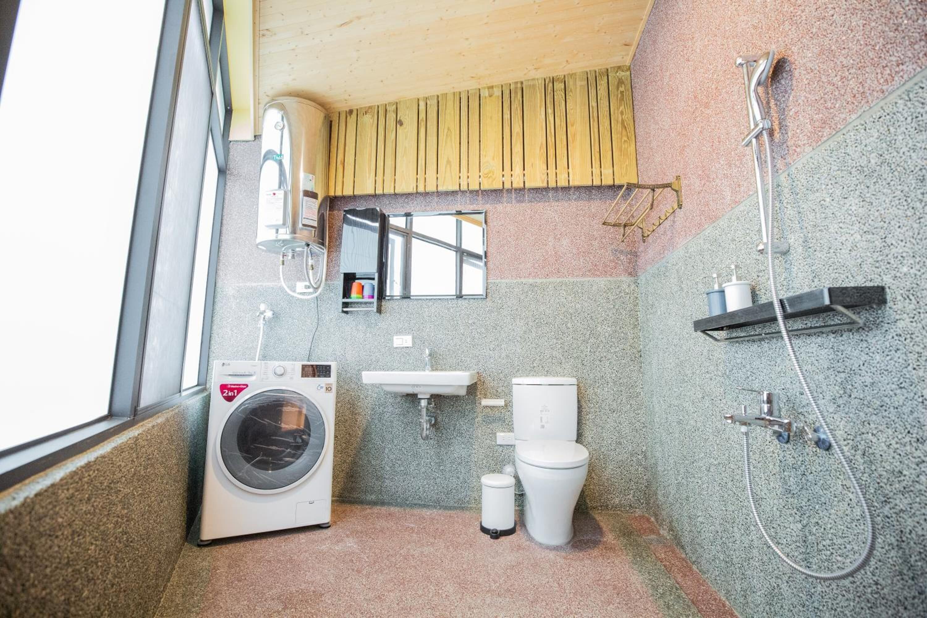 A compact bathroom with a washing machine, sink, toilet, and shower.