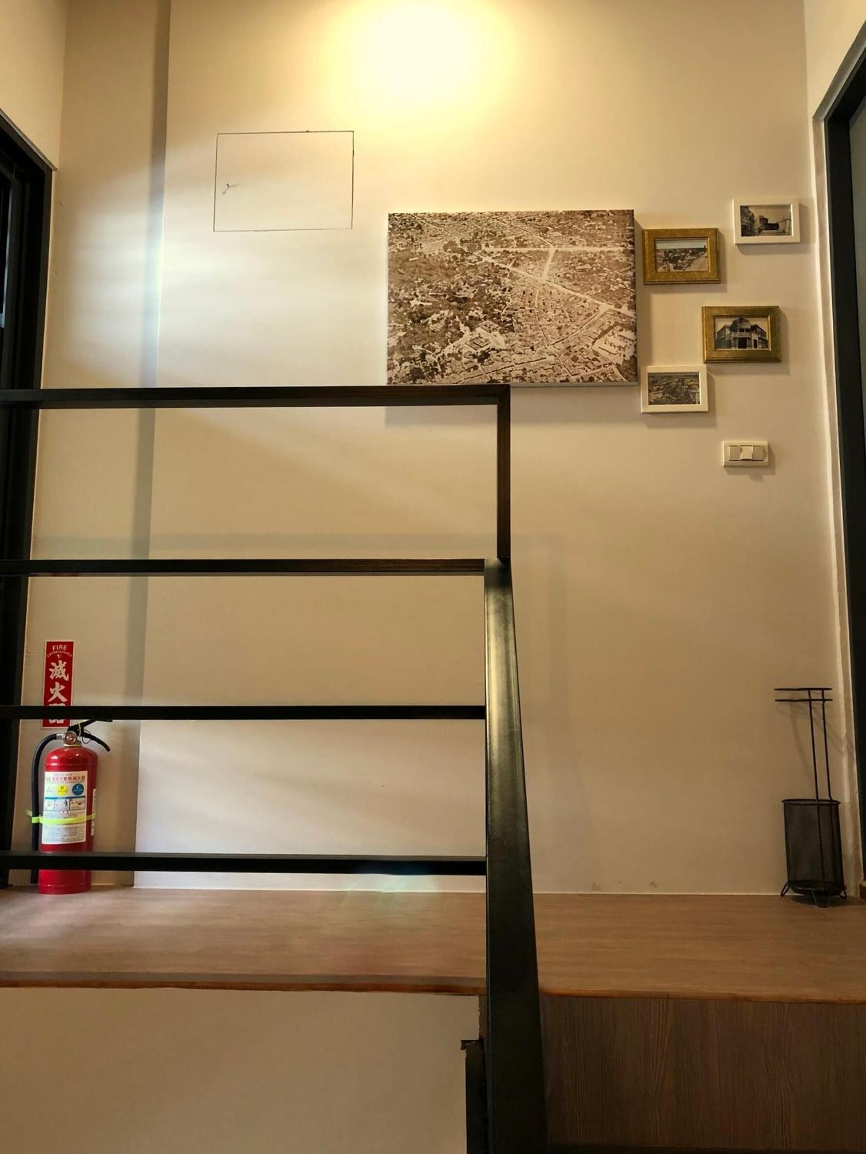 Una habitación con una cama litera, un extintor y un estante en la pared con fotografías.