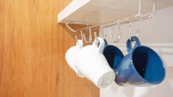 Un perchero metálico con ganchos sosteniendo tazas blancas y azules.