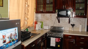 A kitchen with wooden cabinets, a microwave, a stove, and a sink. - New Kingston Serenity at The Oxford (Kingston)