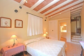 Une chambre à coucher avec un lit, des lampes de chevet, une table à carreaux et une porte donnant sur une salle de bain.