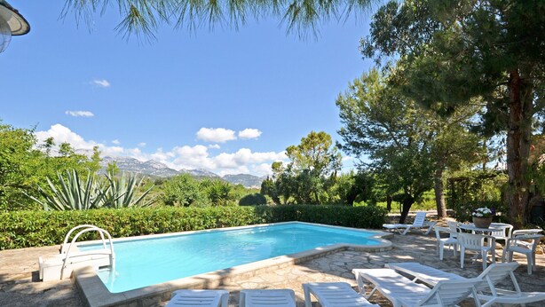 A pool with white lounge chairs and a stone border. - Rustic - Cozy country house with pool in Mancor de la Vall, Mallorca (Inca)